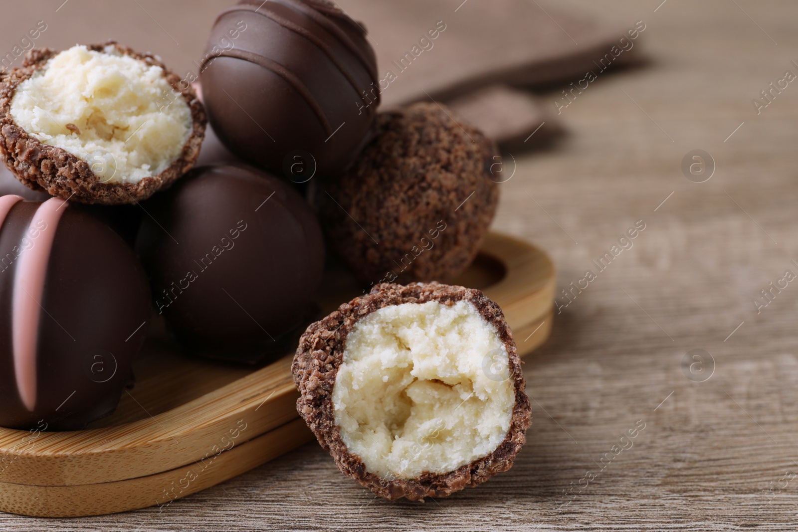 Photo of Many different delicious chocolate truffles on wooden table, closeup. Space for text