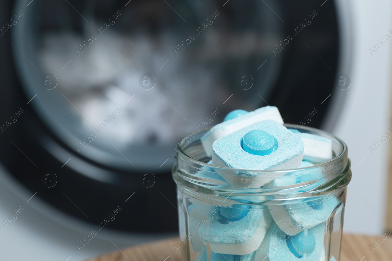 Photo of Jar with water softener tablets near washing machine, closeup. Space for text