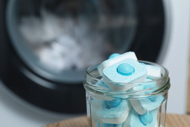 Photo of Jar with water softener tablets near washing machine, closeup. Space for text