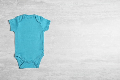 Baby bodysuit on wooden background, top view. Space for text