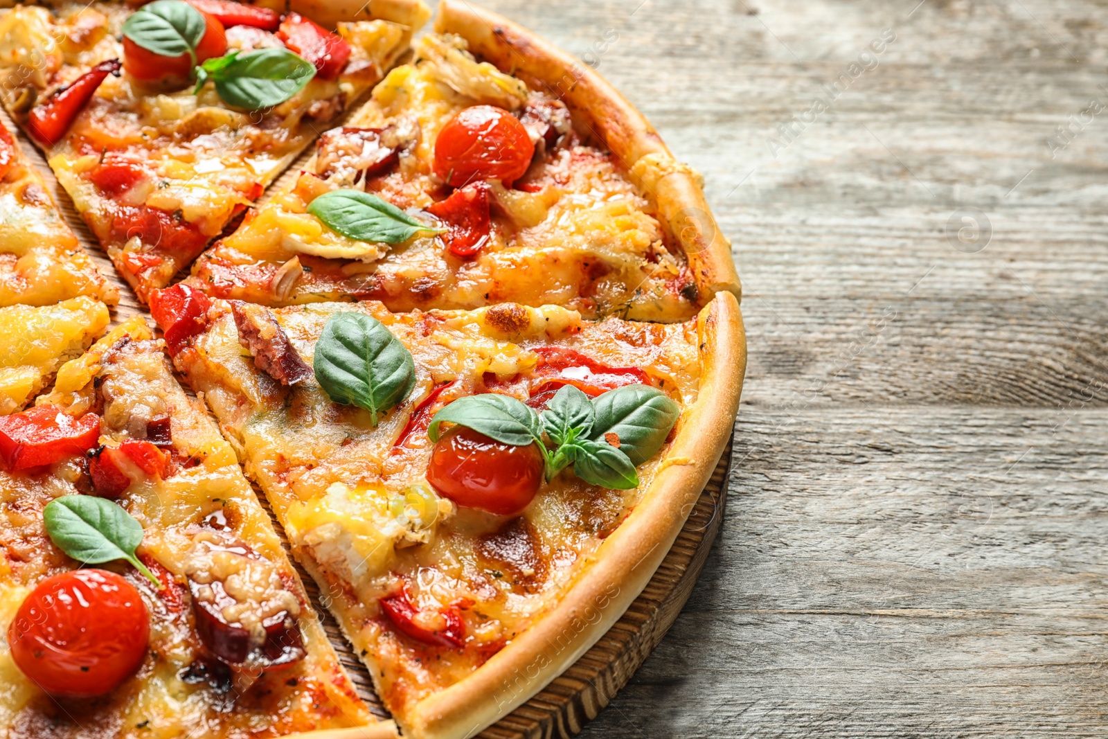 Photo of Delicious pizza with tomatoes and sausages on wooden table