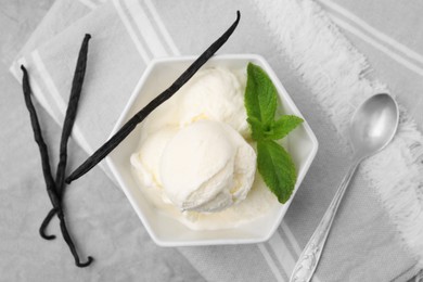 Photo of Delicious ice cream, mint, vanilla pods and spoon on light grey table, flat lay