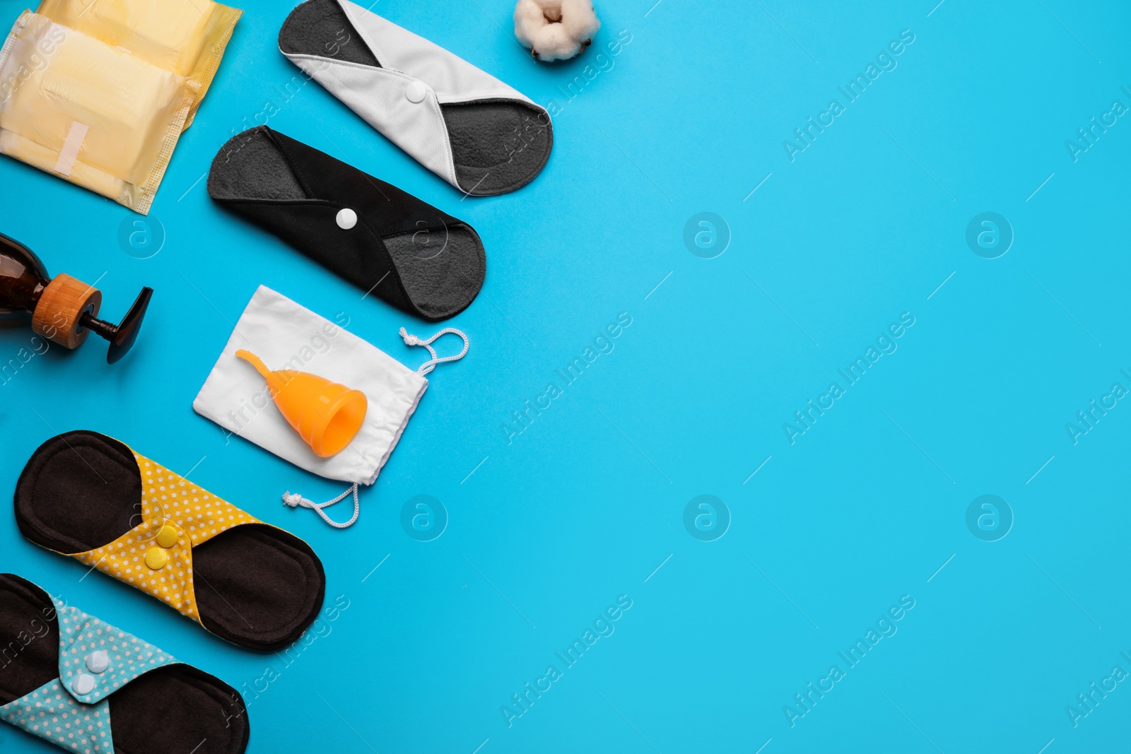 Photo of Cloth menstrual pads and other female hygiene products on light blue background, flat lay. Space for text