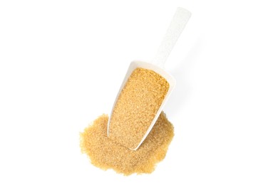 Pile of brown sugar and scoop isolated on white, top view