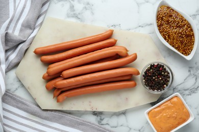 Photo of Fresh delicious sausages, mustard and pepper on white marble table, flat lay