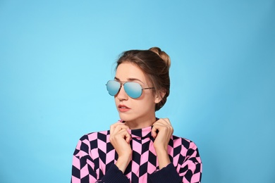 Photo of Young woman wearing stylish sunglasses on blue background