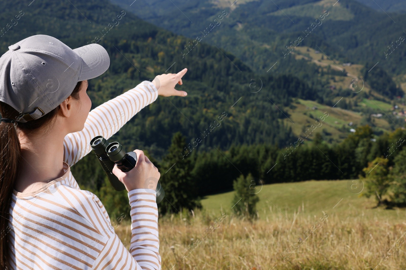 Photo of Woman with binoculars in mountains on sunny day