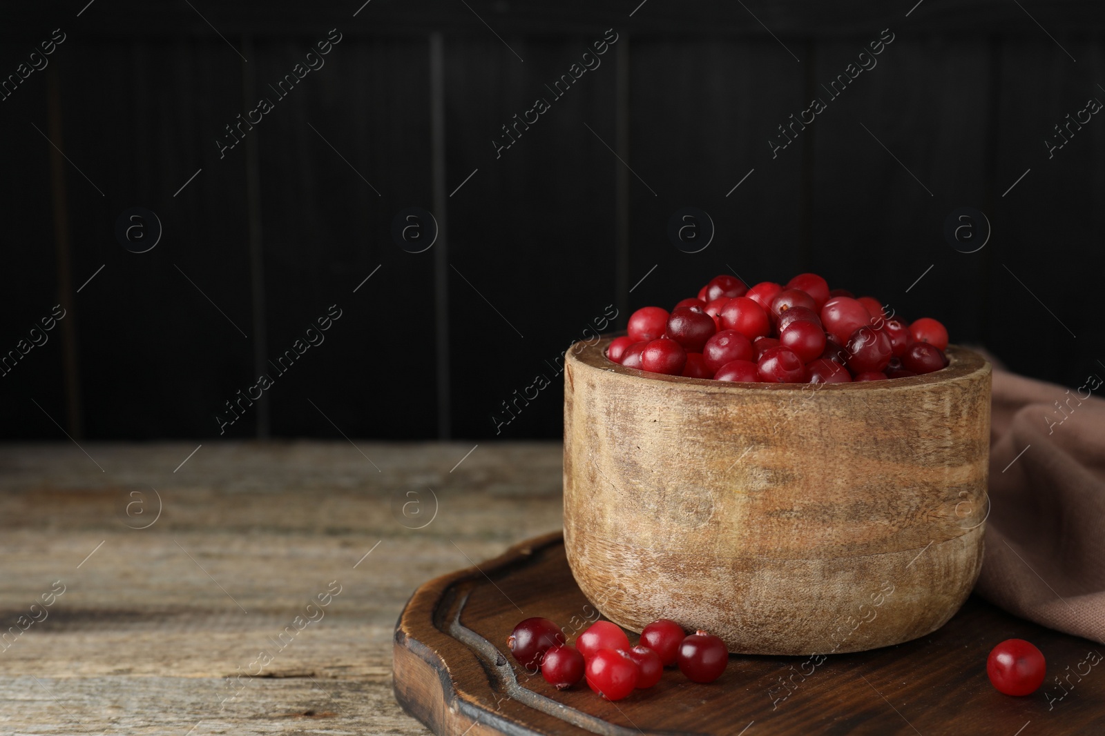 Photo of Cranberries in bowl on wooden table, space for text