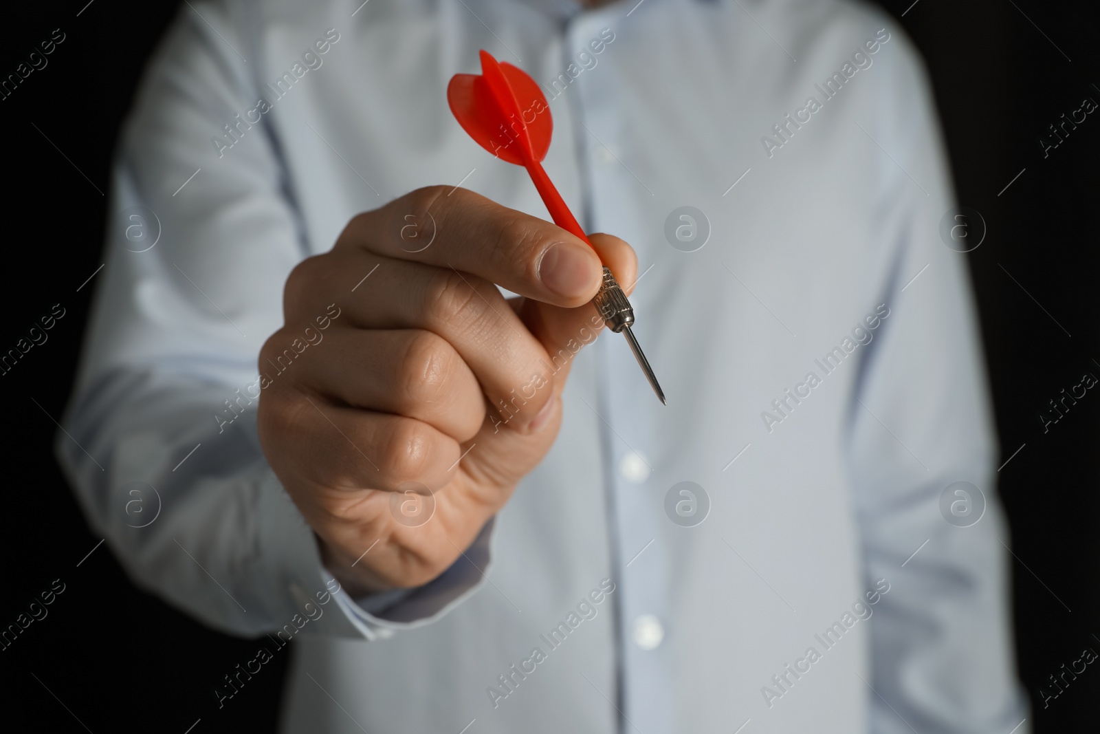 Photo of Man holding red dart on black background, closeup