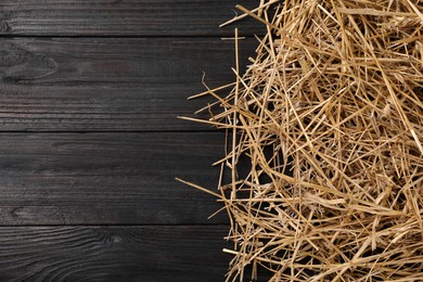 Photo of Dried straw on dark wooden table, top view. Space for text