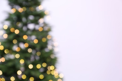 Blurred view of beautiful Christmas tree with fairy lights on white background