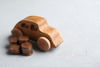 Wooden car model and coins on table. Space for text