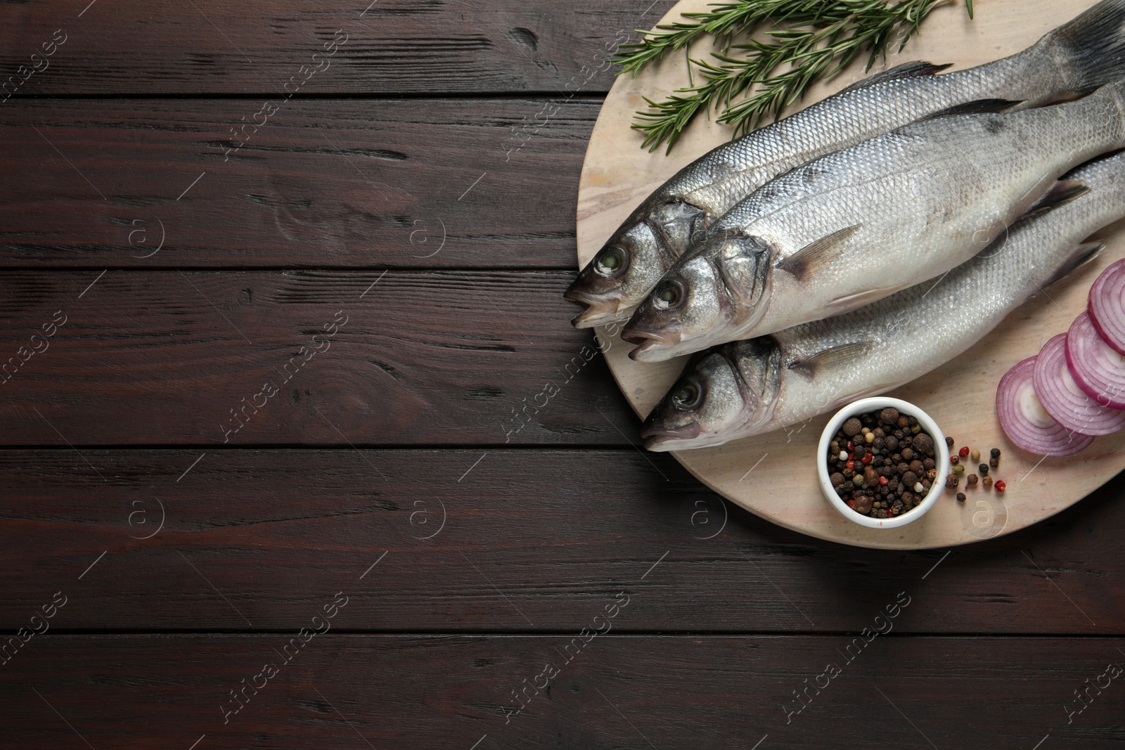Photo of Sea bass fish and ingredients on wooden table, top view. Space for text