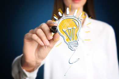 Idea concept. Businesswoman drawing glowing light bulb illustration on virtual screen, closeup