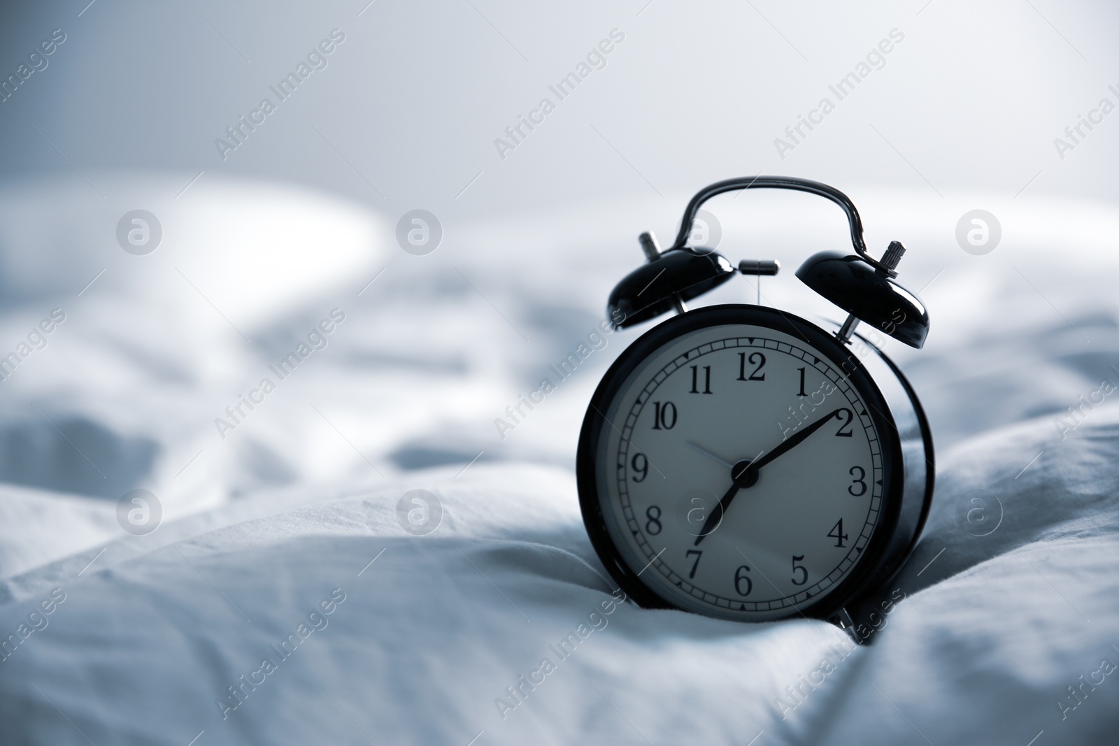 Photo of Alarm clock on bed, space for text. Morning time