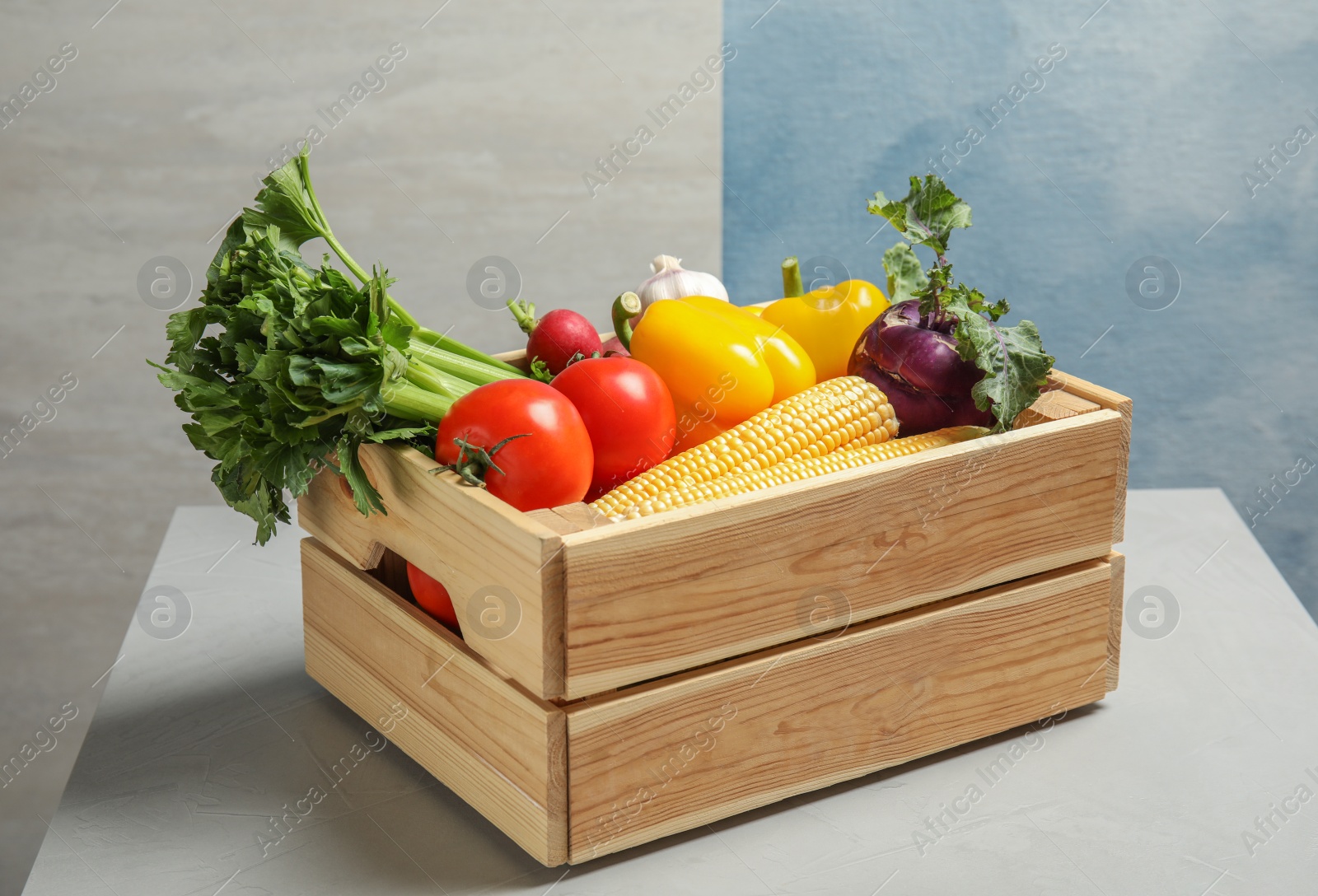 Photo of Wooden crate with fresh vegetables on gray table