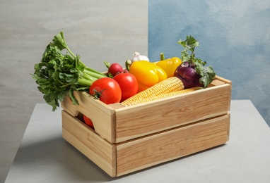 Photo of Wooden crate with fresh vegetables on gray table