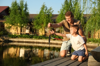 Photo of Dad and son fishing together on sunny day