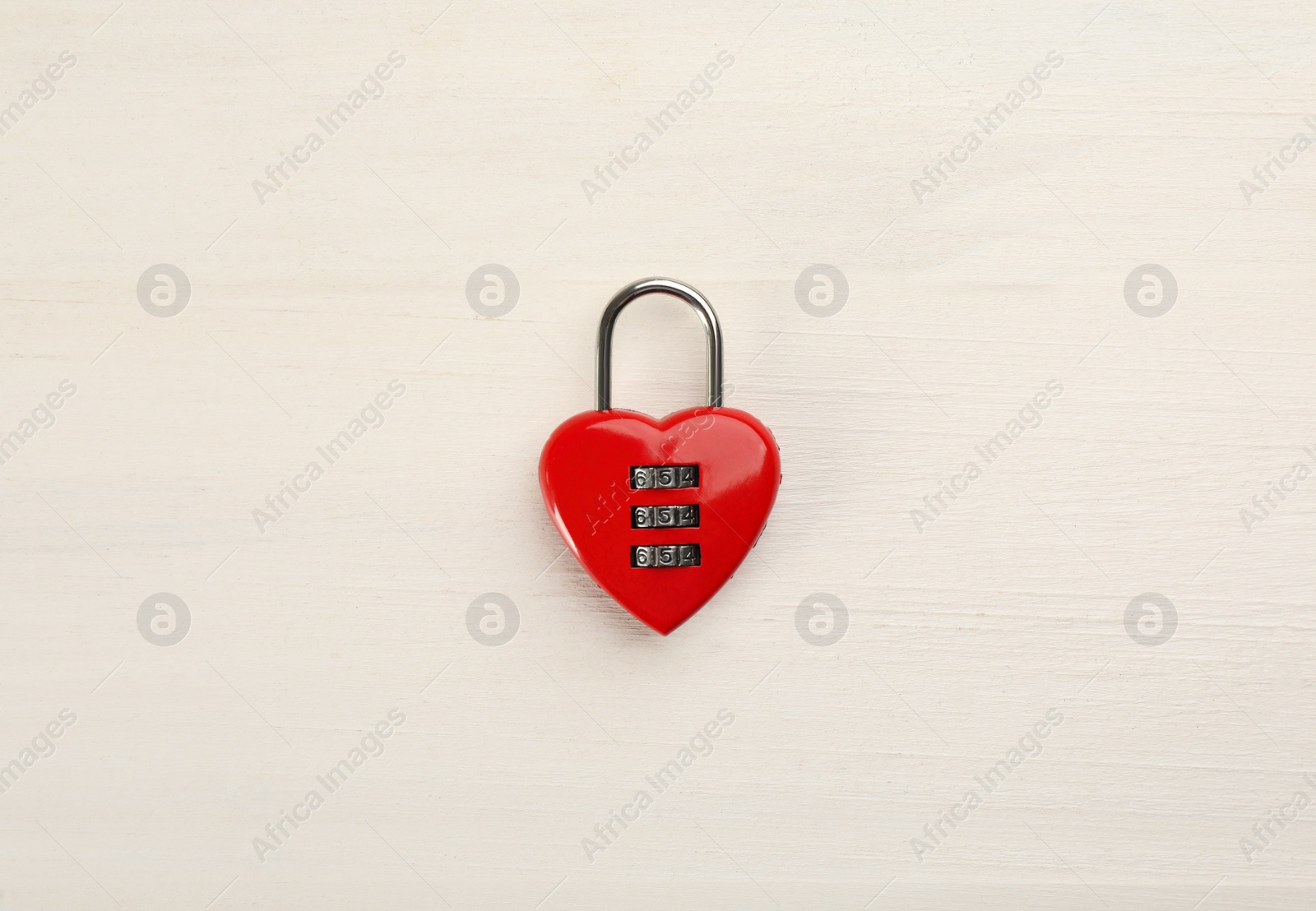Photo of Red heart shaped combination lock on white wooden table, top view