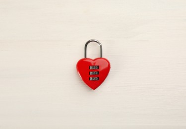 Red heart shaped combination lock on white wooden table, top view