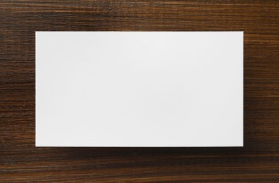 Photo of One blank business card on wooden table, top view. Mockup for design