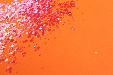 Photo of Shiny bright red glitter on orange background. Space for text