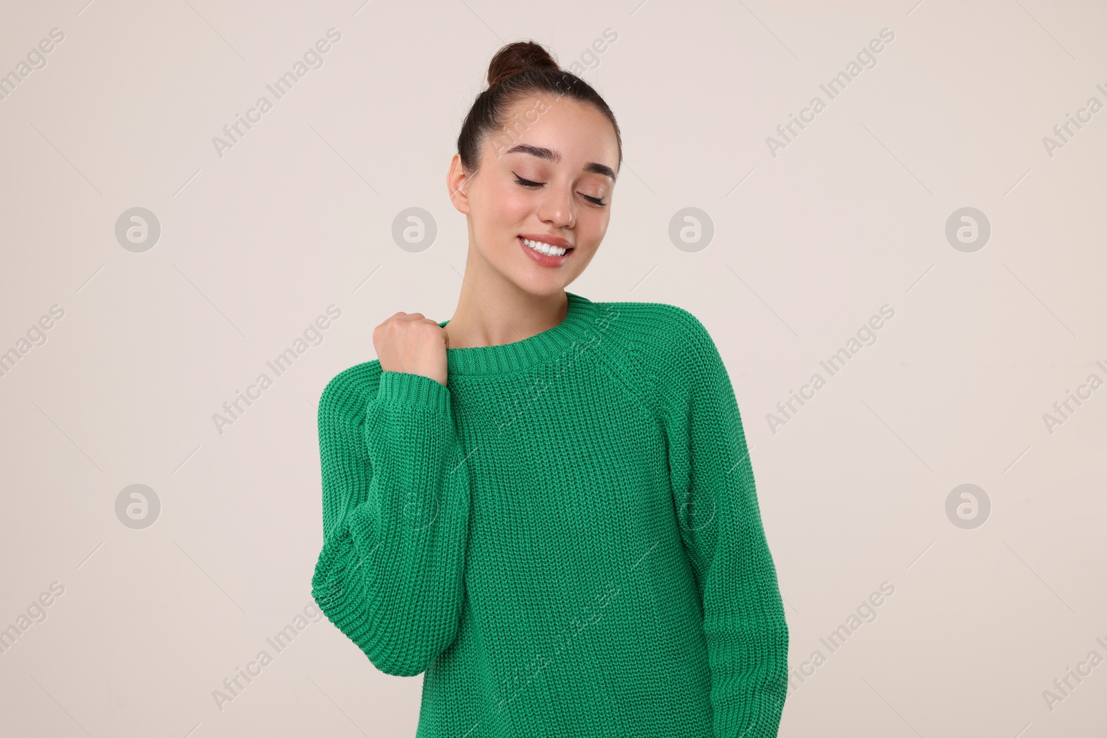 Photo of Beautiful young woman in stylish warm sweater on light grey background