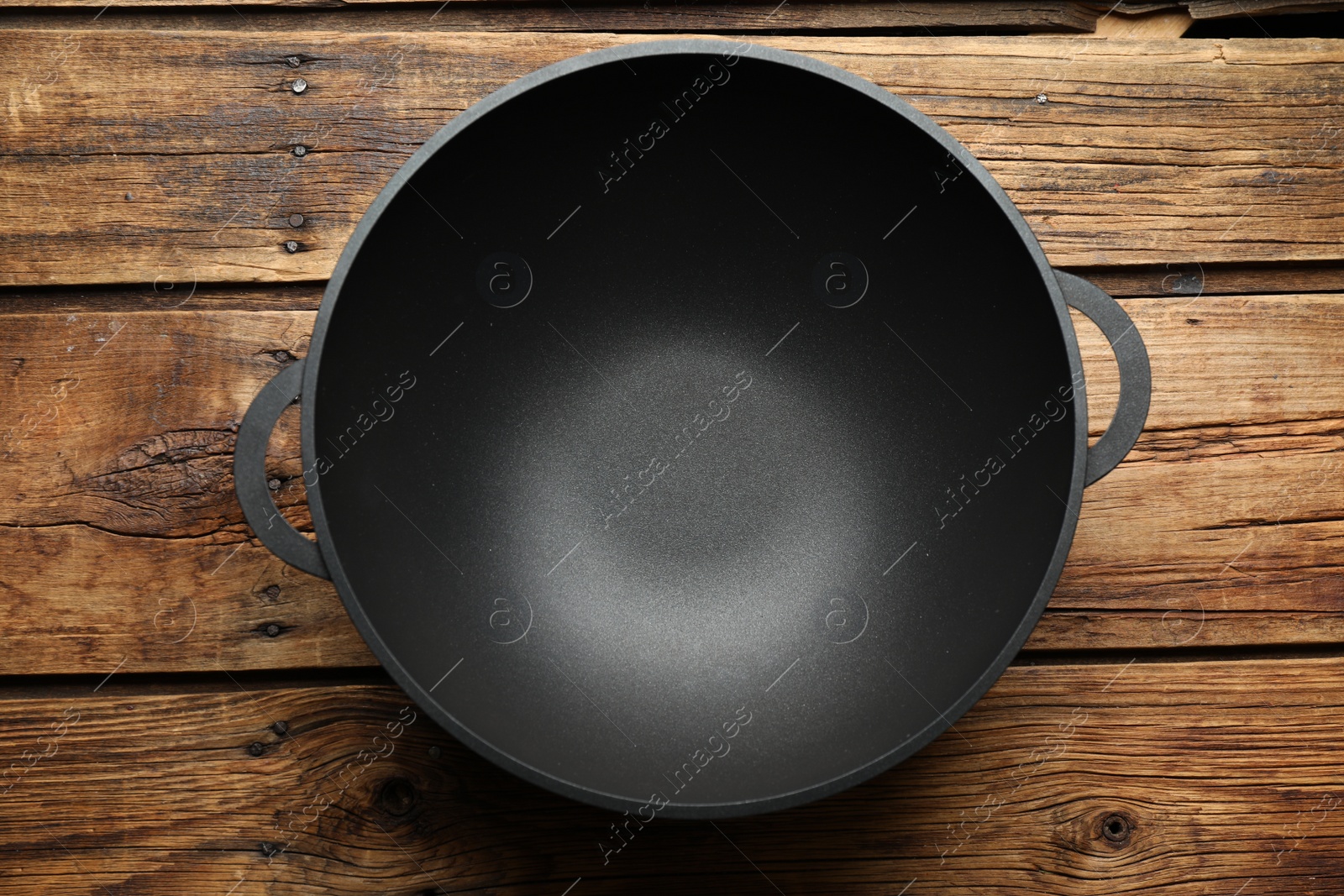 Photo of Empty iron wok on wooden table, top view. Chinese cookware