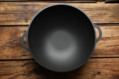 Photo of Empty iron wok on wooden table, top view. Chinese cookware