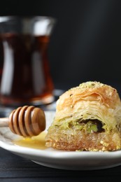 Photo of Delicious fresh baklava with chopped nuts and honey on table, closeup. Eastern sweets