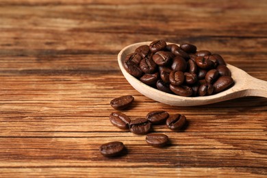 Photo of Roasted beans and spoon on wooden table, closeup. Space for text
