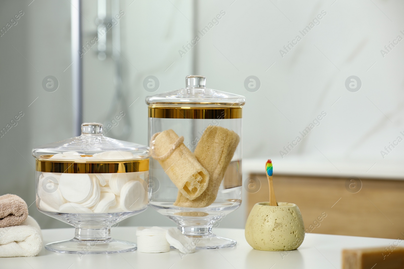 Photo of Composition of glass jar with cotton pads and luffa sponges on table in bathroom. Space for text