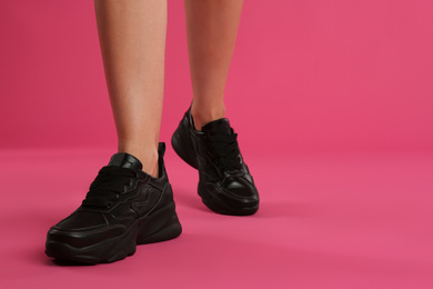 Photo of Woman wearing sneakers on pink background, closeup. Space for text