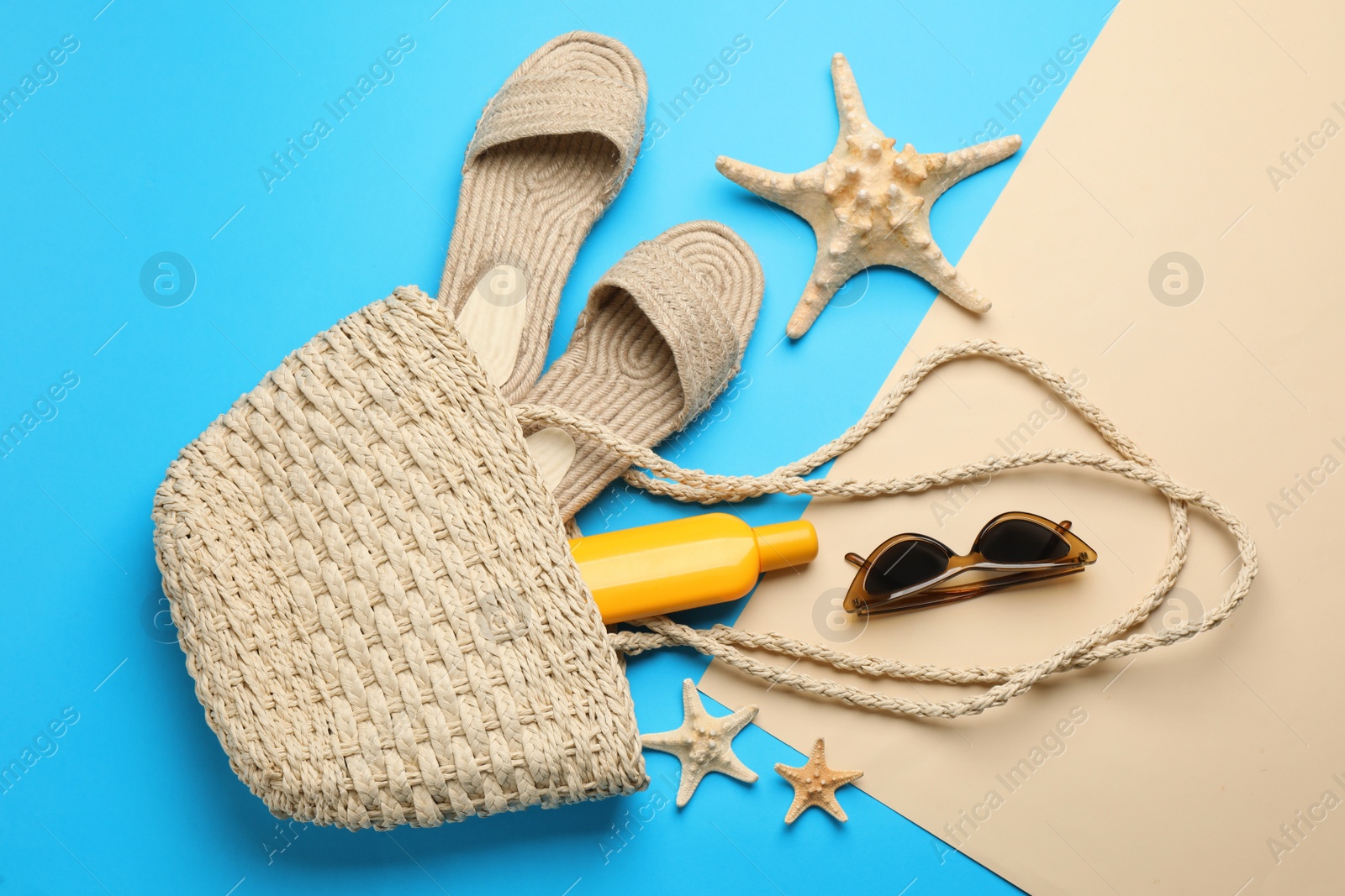 Photo of Stylish bag with beach accessories on color background, flat lay