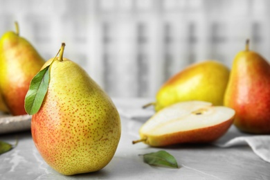Photo of Ripe juicy pears on grey stone table against light background. Space for text