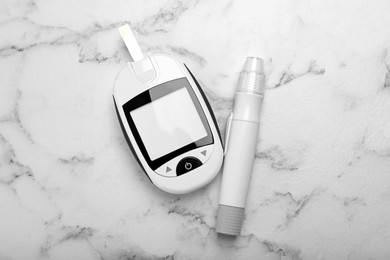 Photo of Glucometer and lancet pen on white marble table, flat lay. Diabetes testing kit