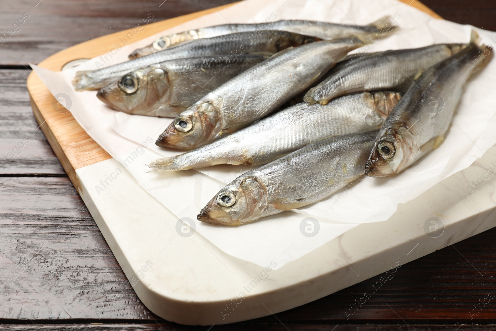 Photo of Fresh raw sprats on wooden table, closeup