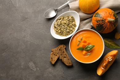 Photo of Flat lay composition with bowl of pumpkin soup and space for text on gray background
