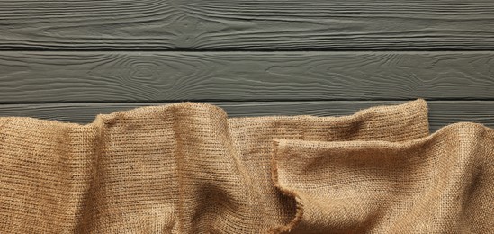 Photo of Burlap fabric on grey wooden table, top view. Space for text