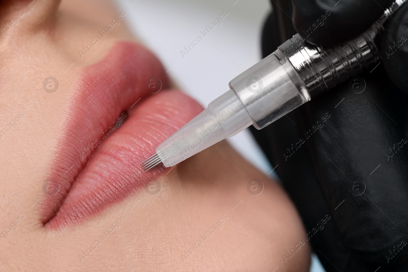 Photo of Young woman during procedure of permanent lip makeup in beauty salon, closeup