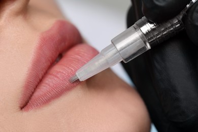 Photo of Young woman during procedure of permanent lip makeup in beauty salon, closeup