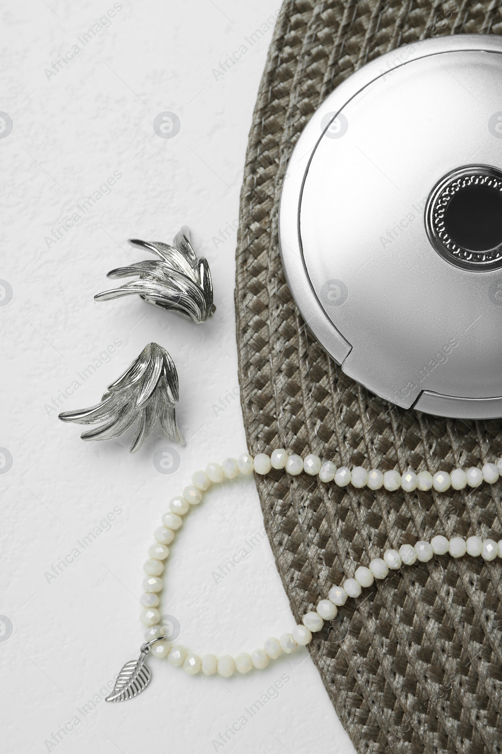 Photo of Elegant earrings, necklace and cosmetic pocket mirror on white table, flat lay