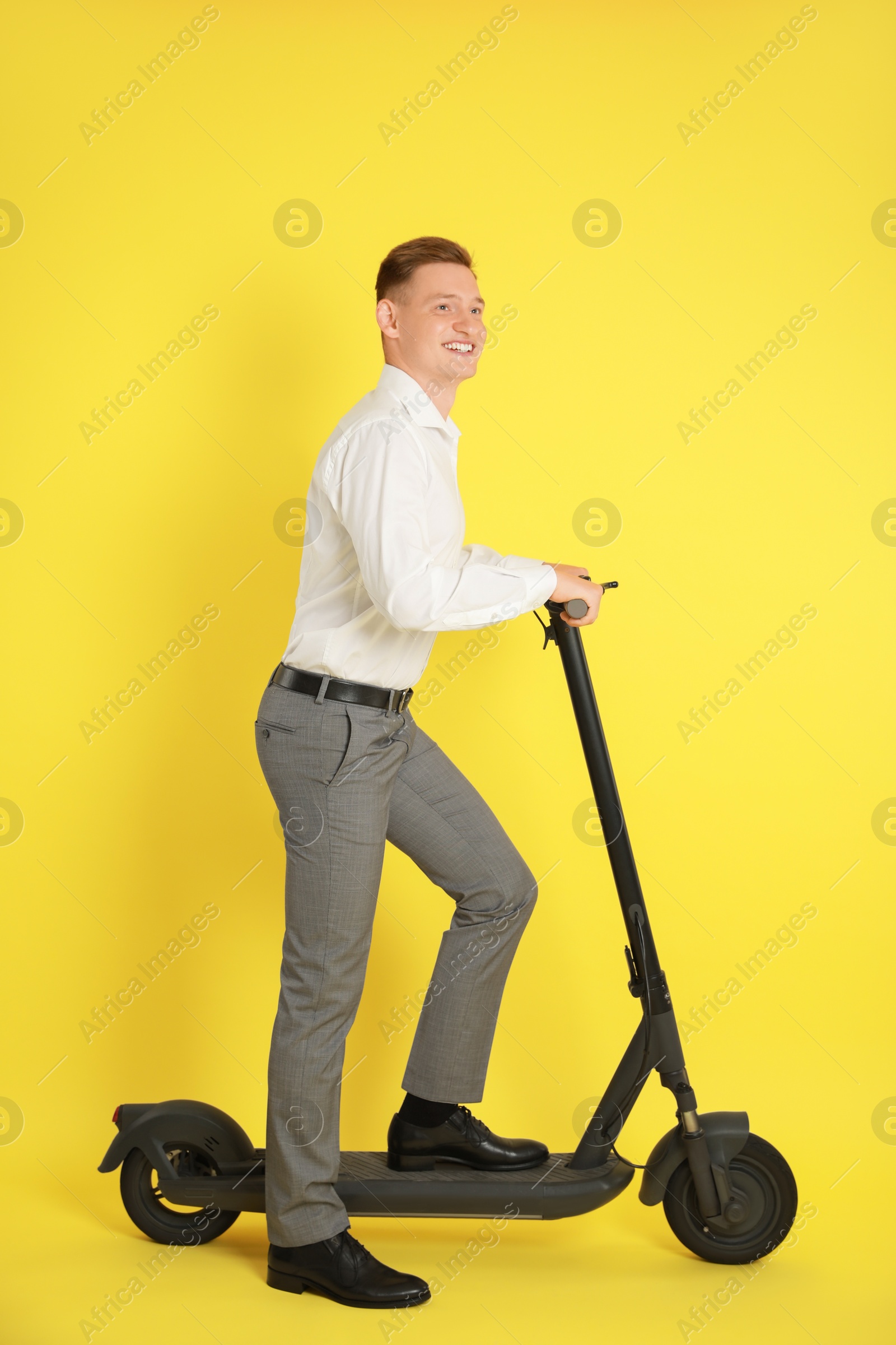 Photo of Happy man with modern electric kick scooter on yellow background