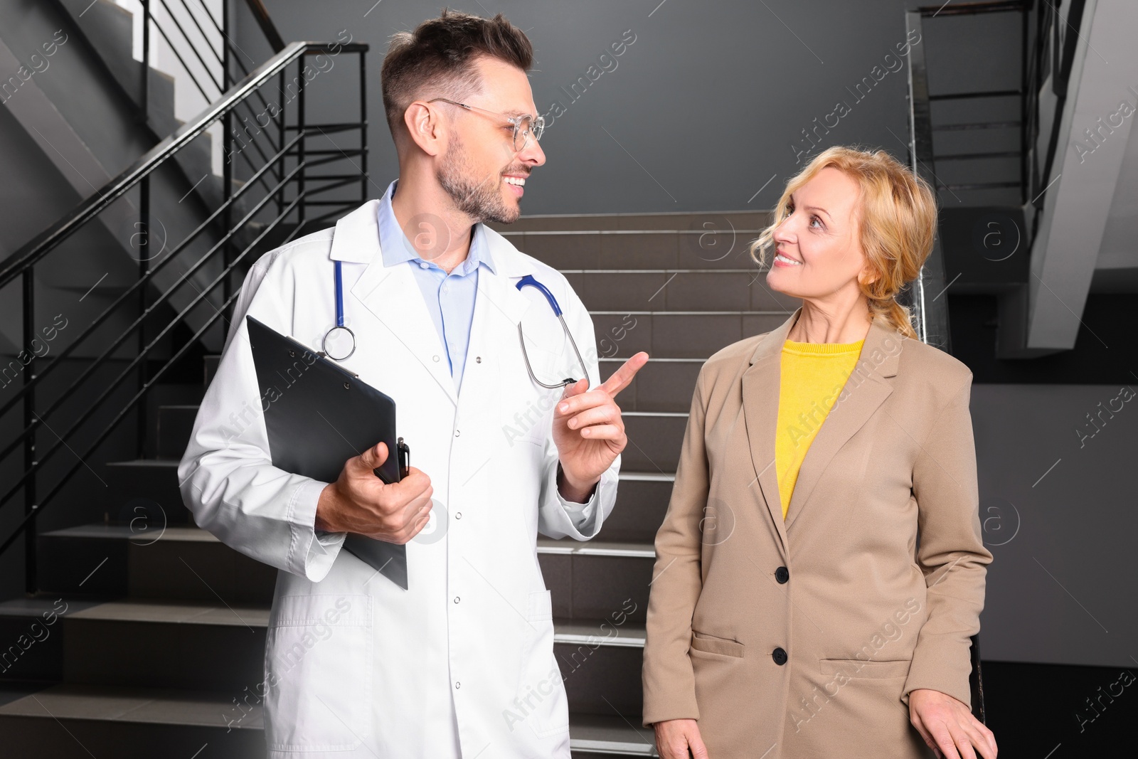 Photo of Happy doctor with clipboard and patient in clinic