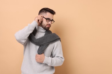 Photo of Handsome man in knitted scarf on beige background. Space for text