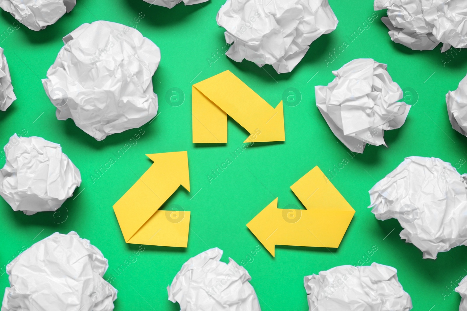 Photo of Recycling symbol and crumpled paper on green background, flat lay