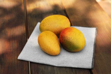 Many tasty mango fruits on wooden table outdoors