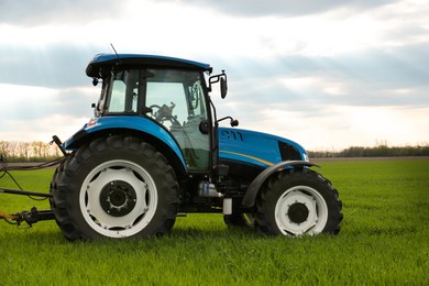 Photo of Modern tractor in field on spring day. Agricultural industry