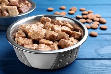 Photo of Wet pet food in feeding bowl on blue wooden table, closeup