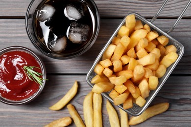 Tasty French fries, soda and ketchup on grey wooden table, flat lay